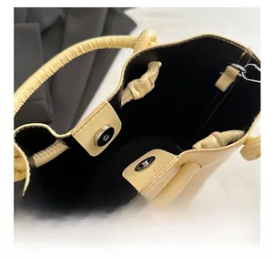 Detail of magnetic silver buckles and black lining inside the creamy yellow handbag