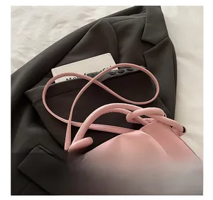 Pink pleated cloud handbag with knotted handle and shoulder strap on a grey blazer