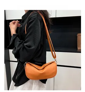 Detailed side view of orange hobo bag with pebble leather texture and adjustable strap