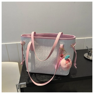 Detail of white quilted tote bag featuring pink leather trim and a peach plush charm