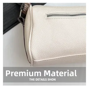 Detail of white lychee leather cylinder bag with silver zipper and woven strap