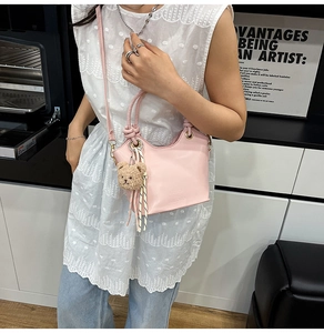 Detail of pink leather bucket bag with teddy bear charm shown in a lifestyle kitchen setting