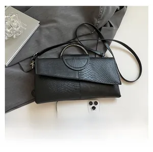 Dettaglio pochette nera in pelle PU con texture a serpente e manico rotondo in metallo
