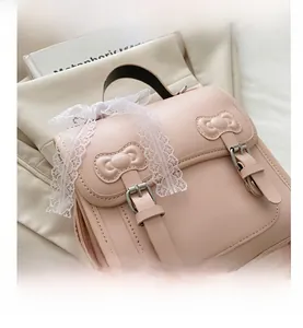 Close-up of pink leather backpack featuring white lace bow and dual buckle details
