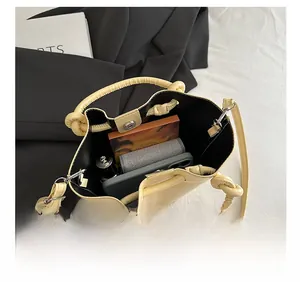 Capacité interne du sac seau en cuir crème montrant téléphone et essentiels