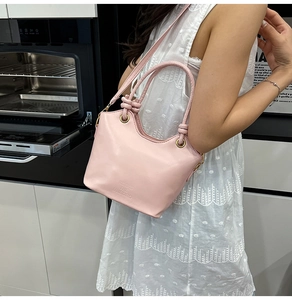 Borsa a secchiello rosa in ecopelle indossata a tracolla con tracolla regolabile e manico