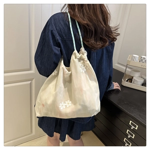 Detail of cream canvas tote bag with white floral embroidery and drawstring closure
