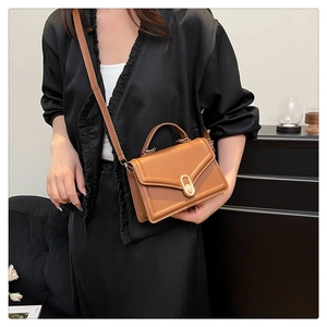 Caramel leather crossbody bag on black ruffle top model with metallic lock detail