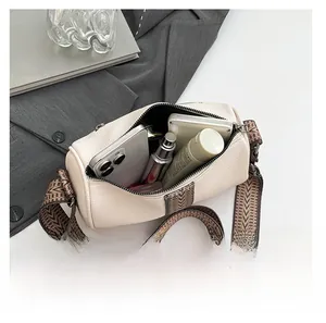 Beige cylinder pillow bag showing large capacity with phone and woven wide strap