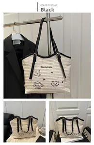 Detail view of woven straw tote bag with black cat embroidery and PU leather straps