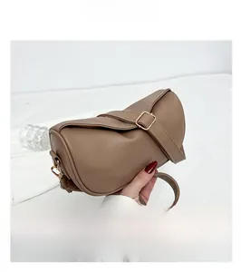 Detail of brown litchi pattern cylinder bag showing soft leather texture and golden buckle