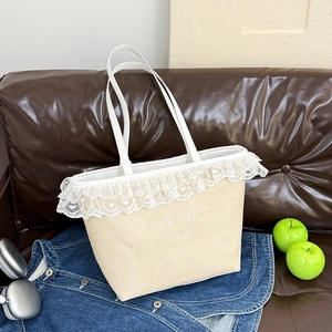 Beige tote bag with white lace trim and embroidery shown in a lifestyle fashion setting
