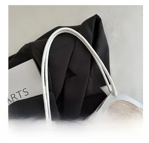 Detail of white leather handles and beige woven texture on a minimalist tote bag