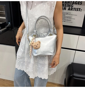 Borsa a secchiello metallizzata argento con ciondolo a orsetto marrone su una modella