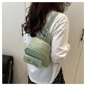 Close-up of mint green mini backpack with bow detail and circular handle on model