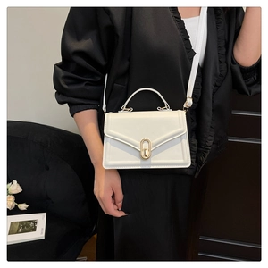 Détail d'un sac bandoulière blanc crème avec fermoir en métal doré et fine bandoulière