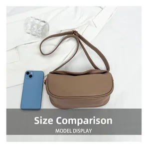 Brown lychee leather crossbody bag size comparison with a smartphone on white fabric