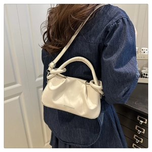 Dettaglio di una borsa a mano increspata bianco crema con tracolla regolabile e fibbie