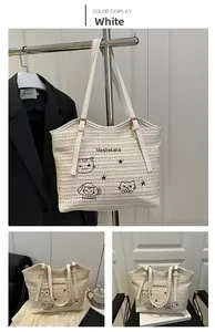 Close-up of white woven tote bag with cat embroidery and adjustable leather strap