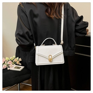 Side view of woman wearing a white square leather crossbody bag with gold buckle