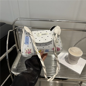 Stylish white crossbody bag with black polka dots and cartoon patches on industrial shelf