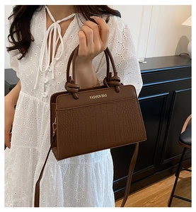 Detail of brown crocodile pattern shoulder bag with gold 'FASHION BAG' lettering