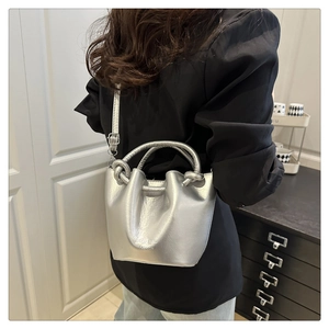 Detail view of silver bucket bag with knotted handle and fashion lettering on side