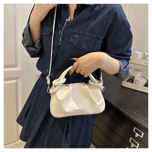 Detail of white cloud pleated handbag with a unique knotted ring handle and brand logo