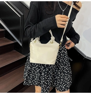 Detail of cream white bucket bag with wavy edge design and embossed logo branding