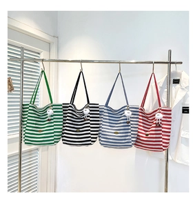 Detail view of colorful striped canvas tote bags with plush ball charms on display