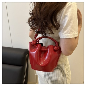 Macro shot of red patent leather bucket bag with knotted handle and embossed logo