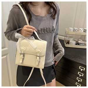 Detail view of the lace bow decoration and metal buckle on this cream white backpack