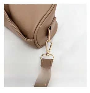 Detail of premium golden metal buckle and textured brown lychee leather bag strap