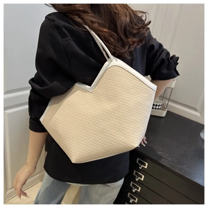 Detailed back view of a person carrying the large woven tote bag with white leather trim