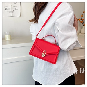 Detail of red matte leather crossbody bag featuring an elegant golden oval twist lock