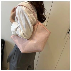 Detail of pink woven tote bag showing premium texture and leather shoulder strap