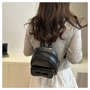 Close-up of black matte leather mini backpack with 3D bow detail and double zipper