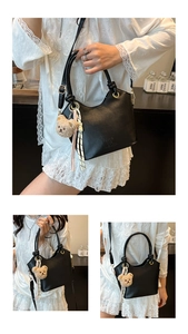 Dettaglio borsa a secchiello in pelle nera con ciondolo a forma di orsetto e foulard a righe