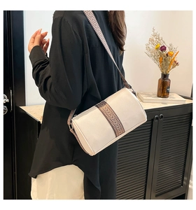 Detail of white boston bag with textured fabric and vintage woven strap on model