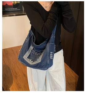 Detail of distressed denim hobo bag with large front pocket and frayed edge design