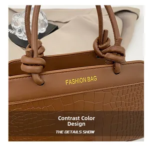 Detail of two-tone brown tote featuring smooth leather and crocodile embossed texture