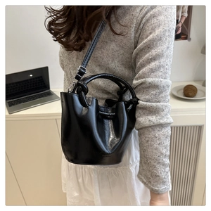 Close-up of black bucket bag with debossed lettering and adjustable shoulder strap