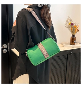 Close-up of bright green cylinder pillow bag with black and white geometric woven strap