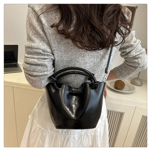 Vue détaillée du sac seau noir brillant avec l'inscription HEW BAG FASHION