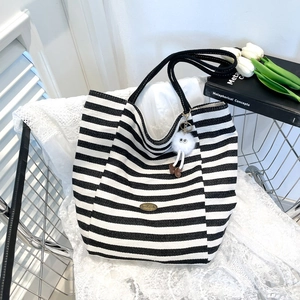 Minimalist black and white striped canvas tote bag with a plush doll charm on white lace