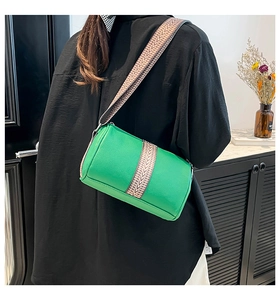 Detail of green cylinder leather bag with lychee texture and woven geometric strap