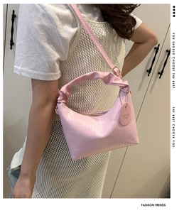 Gros plan du sac à main rose avec plis verticaux et détail de l'étiquette mode