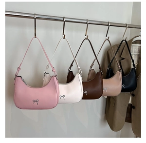 Five assorted colors of hobo crescent bags with bow accents on a display stand