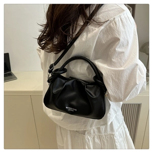 Detail of black pleated cloud bag with Ben Sherman logo worn by a model in a lifestyle setting