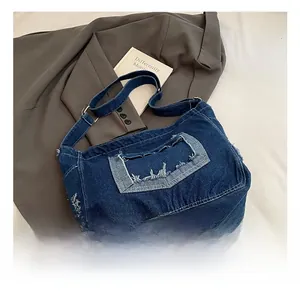 Detail of dark blue denim crossbody bag with frayed edge pockets and adjustable strap